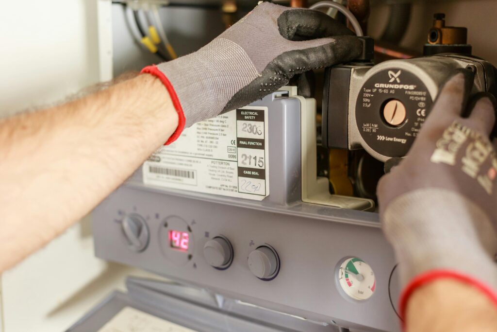 Close-up of hands adjusting a boiler system with precise instrumentation, showing maintenance work.